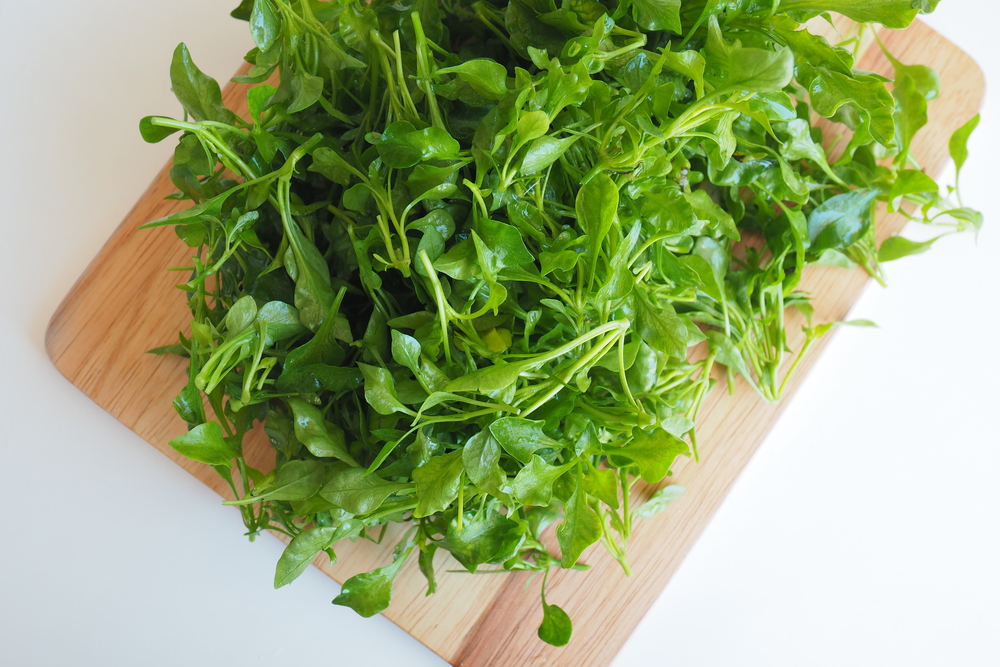 A bunch of watercress on a wooden board